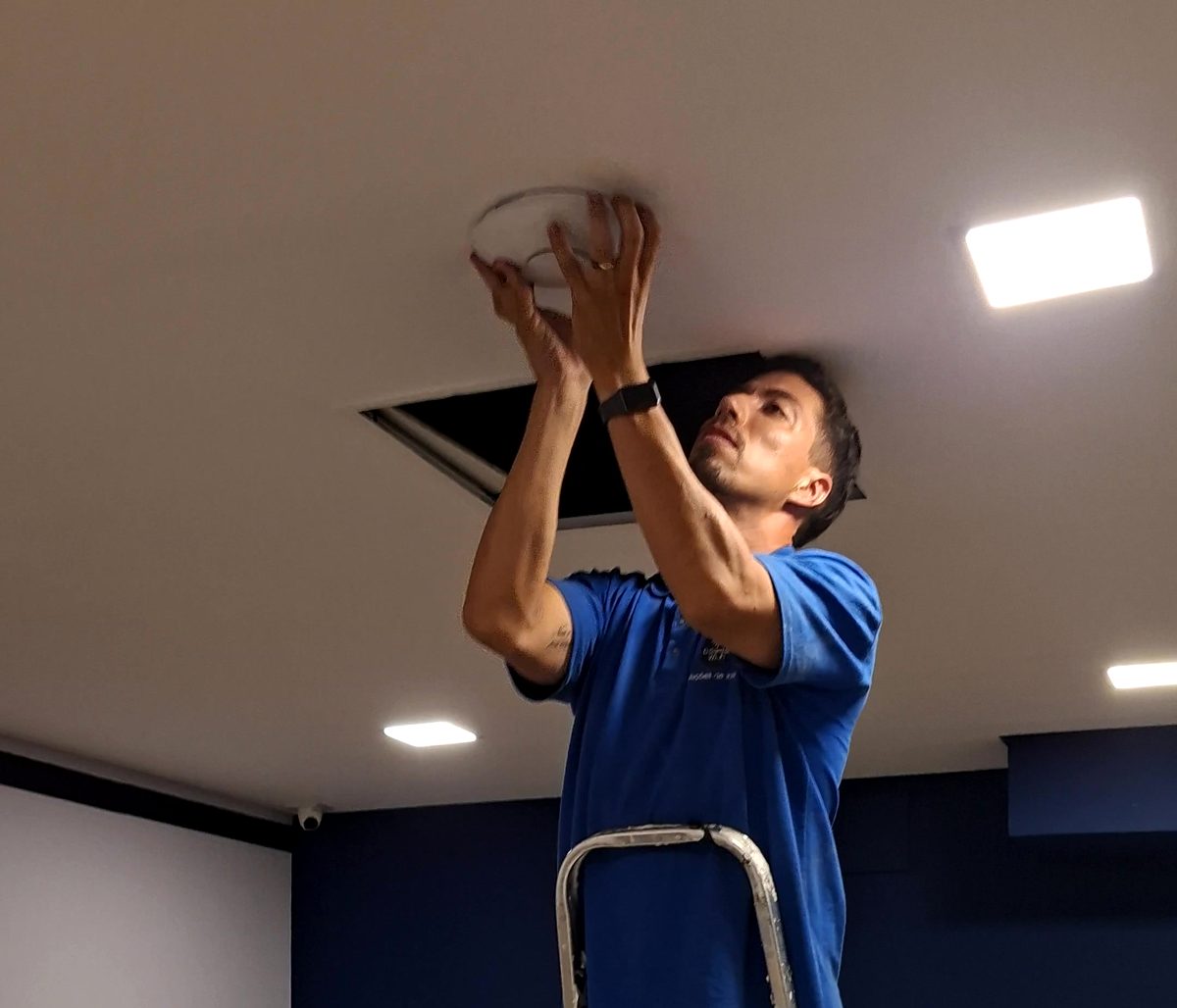 Rafael instalando um access point no forro de um escritório
